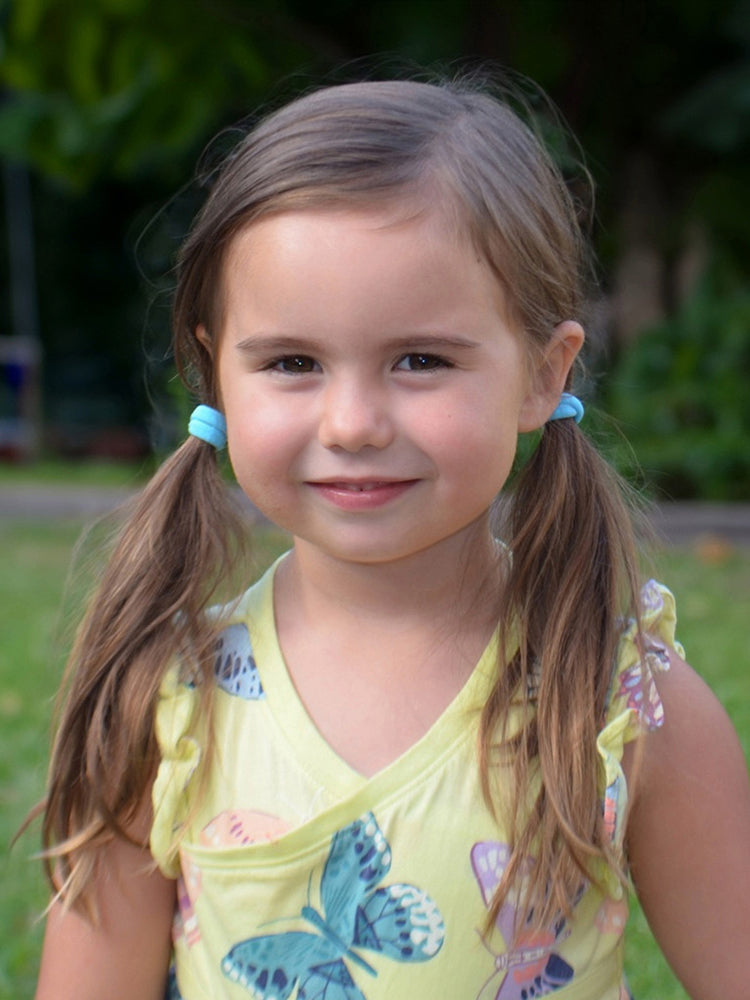 Young girl wearing pigtails using Heliums Small Seamless Hair Ties in blue