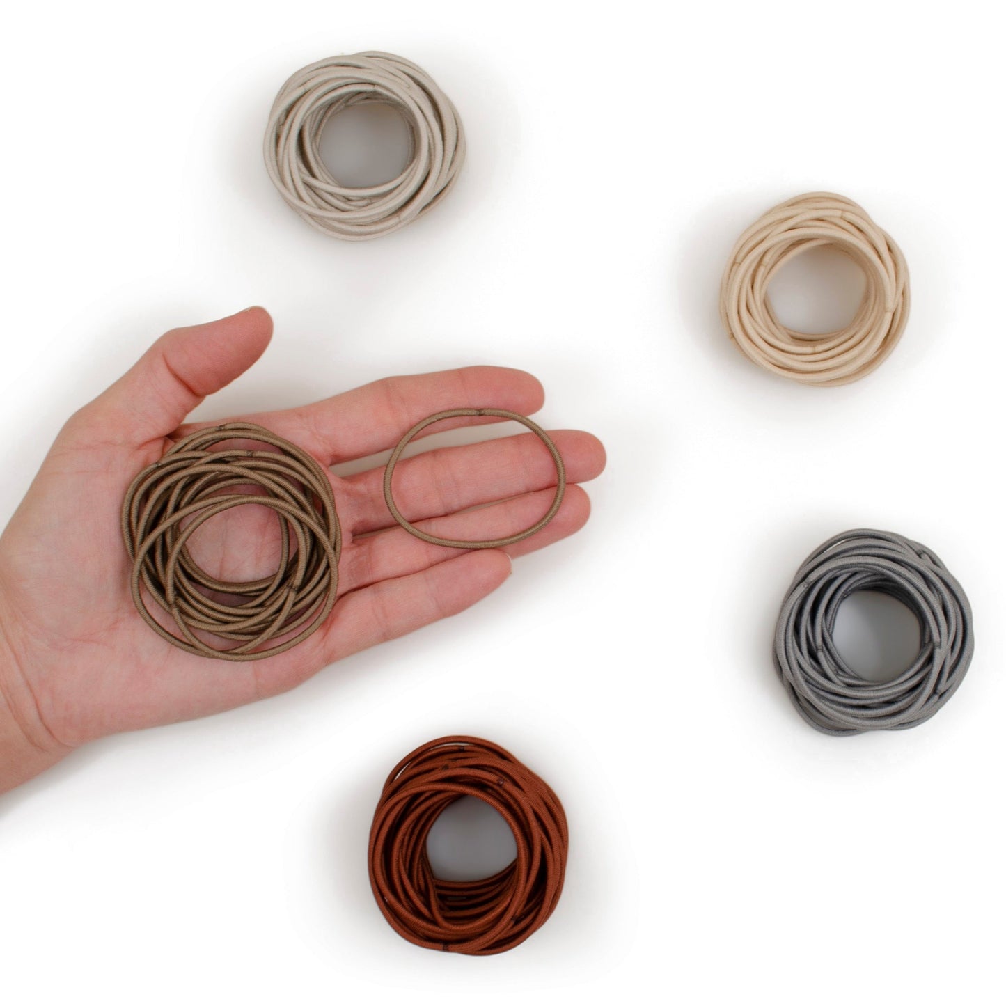 2mm Hair Elastics in 5 neutral shades with woman's hand