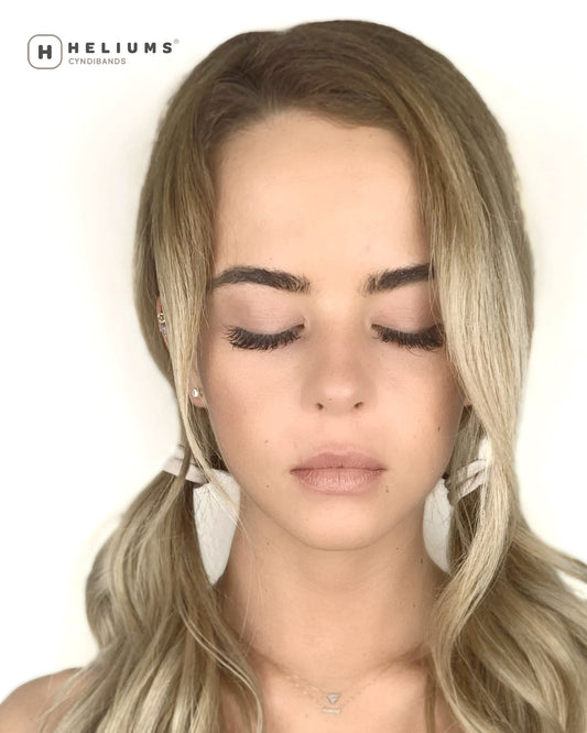 Blonde woman wearing low pigtail ponytails secured with soft HELIUMS Cyndibands seamless hair ties.