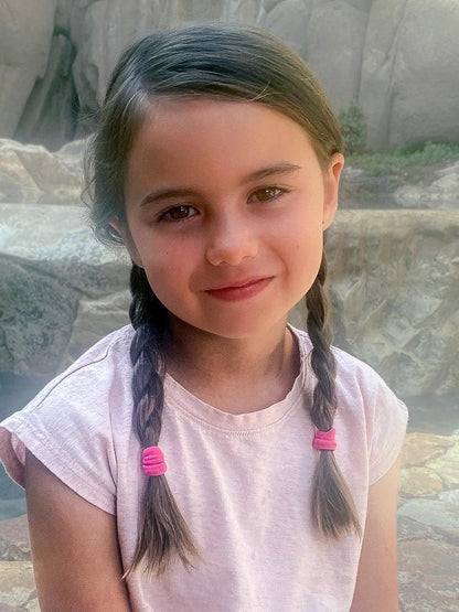 Girl wearing 2 braids using Heliums Small Seamless Hair Ties in pink