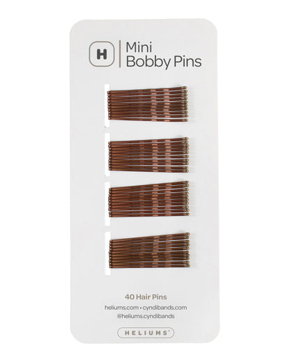 Heliums mini hair pins in brown shades, displayed on a white backing card with the Heliums brand logo.